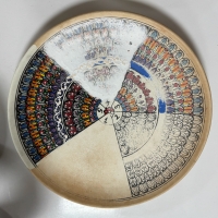 How to make a beautiful plate. First an outliner draws in the design and it is fired the first time. Then it's painted by another artist, and the paint is covered with a glaze. When it is fired a second time the colors pop out under the striking finish. Ömürlü Seramik, Avanos.