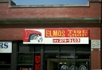 Stoic mechanic works on a wheel, Elmo's Tire Shop, Montrose Avenue at Avers. Elmo's retired this sign long ago.